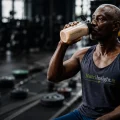 Fit man drinking a protein shake in a gym while supporting weight loss and healthy nutrition goals.