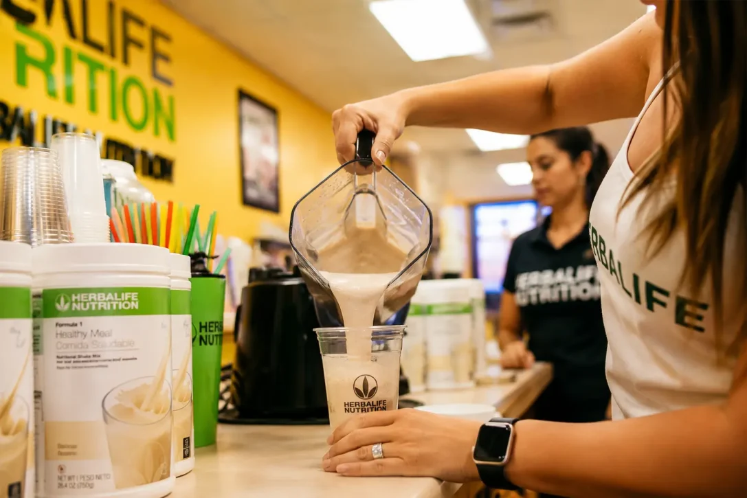 Herbalife Nutrition Club staff preparing a Formula 1 protein shake in a modern wellness cafe.